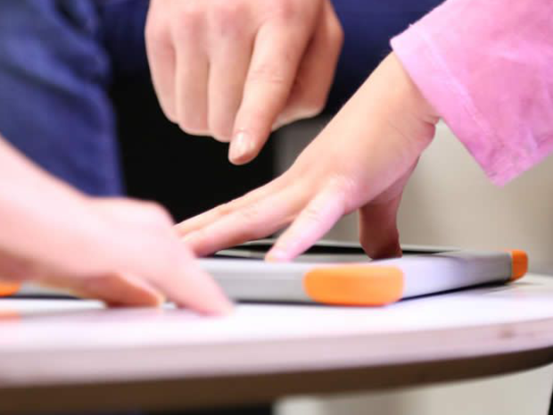 Mains posées sur une tablette numérique de la Fondation Orange